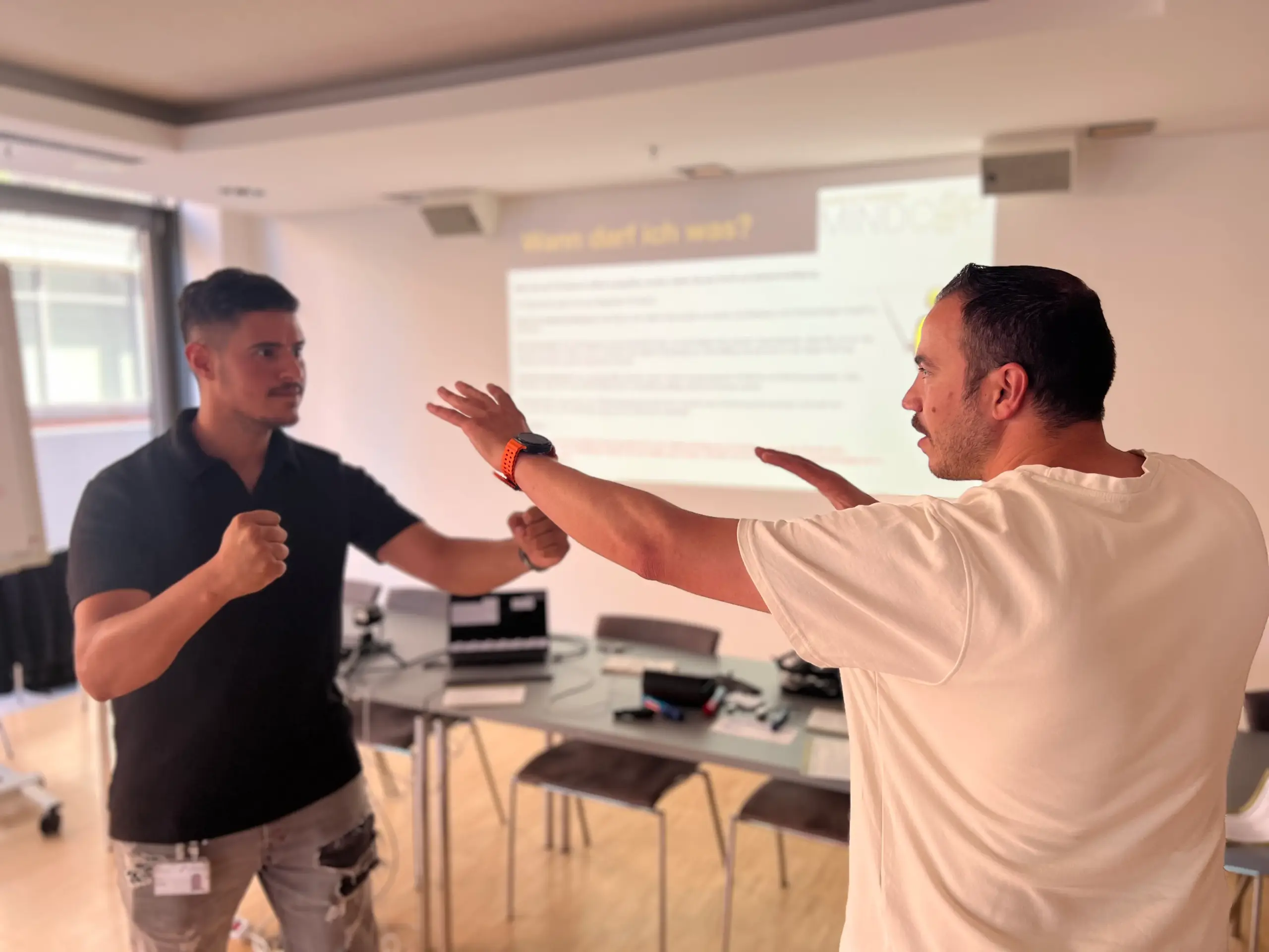 Zwei sich gegenüberstehende Personen mit vor sich ausgestreckten Armen im Deeskalationstraining
