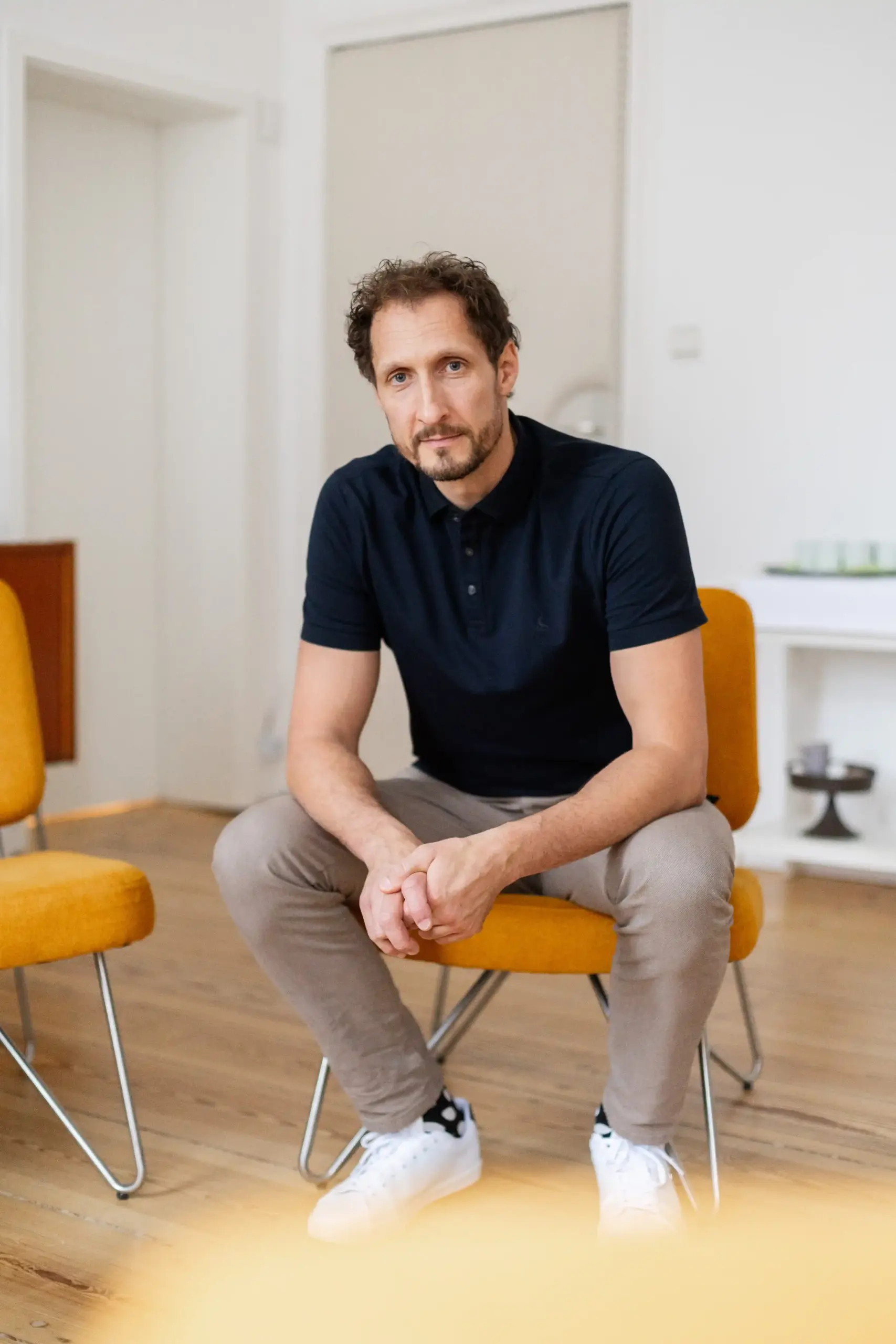 Training für Konfliktsituationen: Portrait von MINDCOP Gründer Marco Winzer auf einem Stuhl sitzend und in die Kamera lächelnd