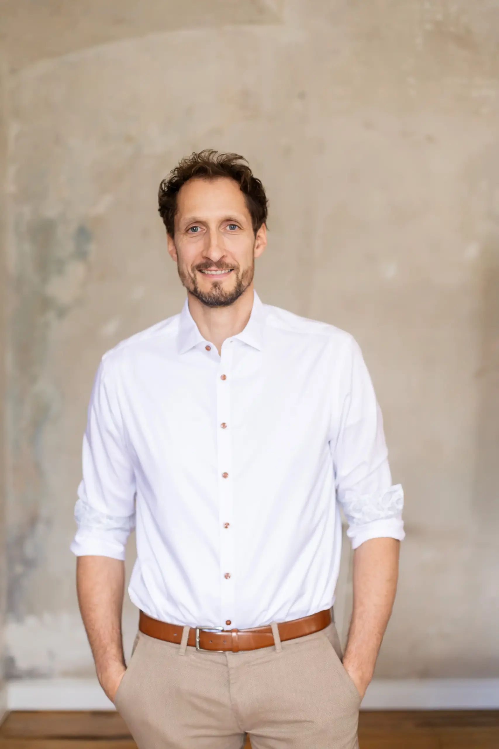 Portrait von MINDCOP Marco Winzer im weißen Hemd vor einer beigefarbenen Wand
