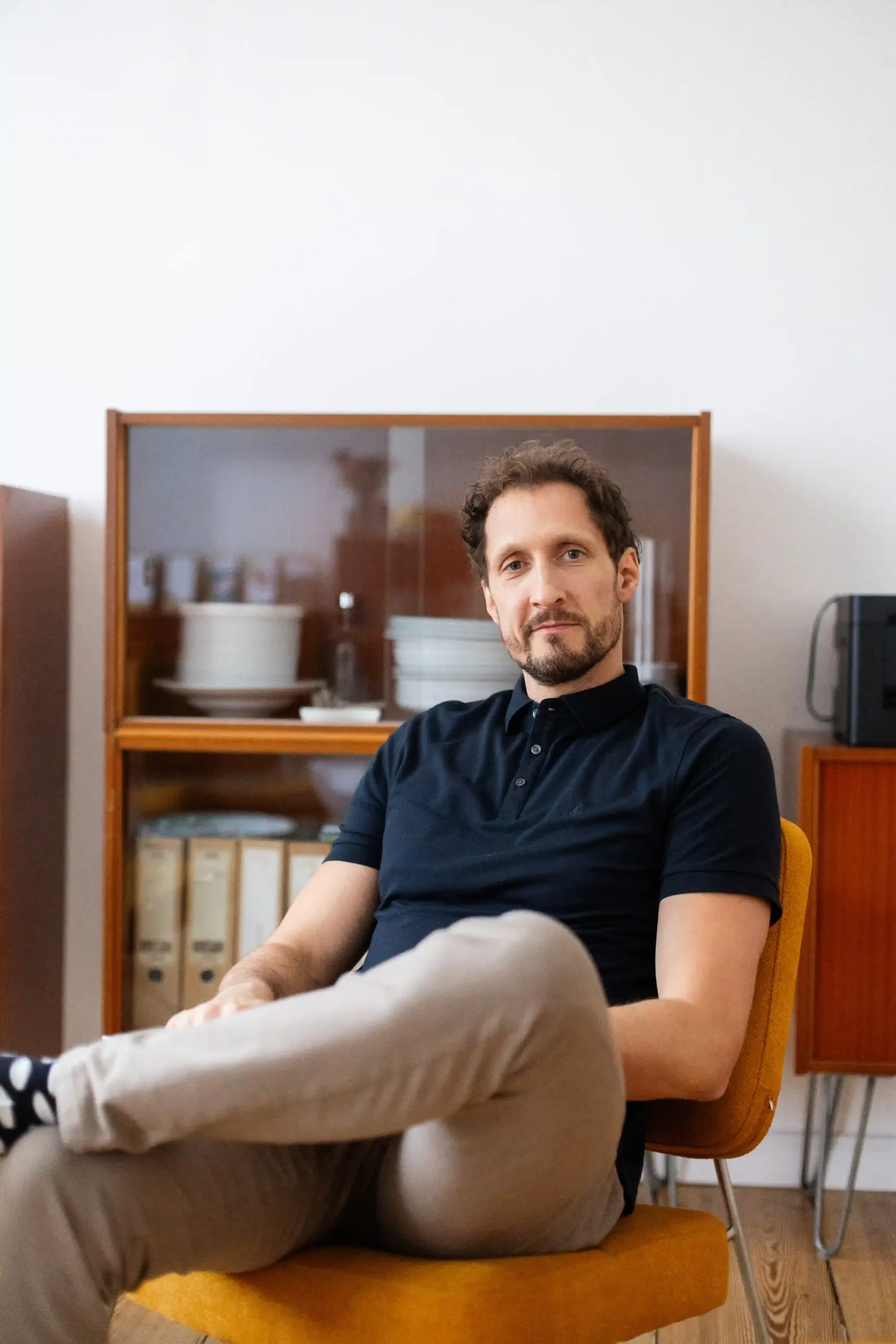 Training für Konfliktsituationen: Portrait von MINDCOP Gründer Marco Winzer auf einem Stuhl sitzend und in die Kamera lächelnd