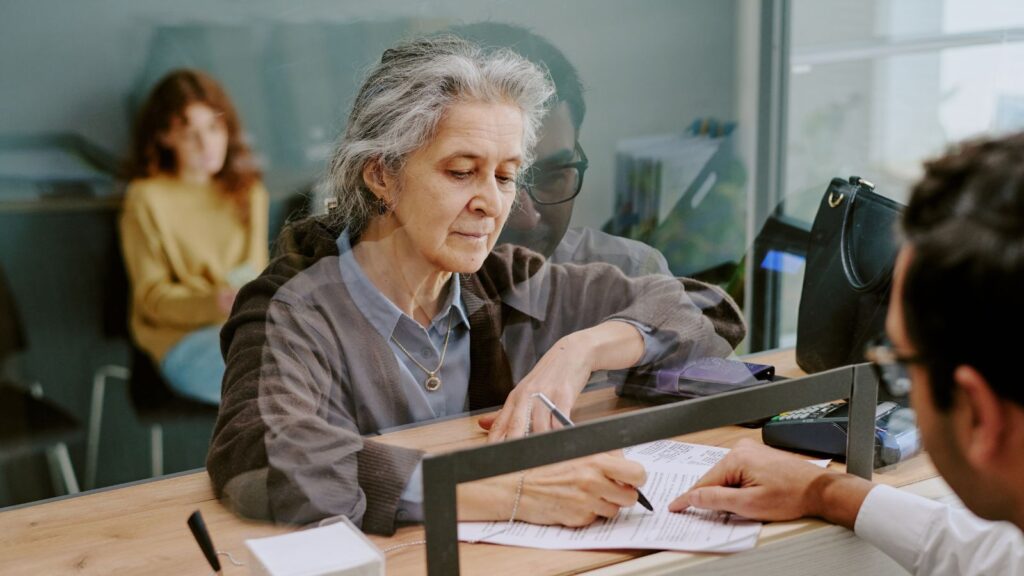 Konflikte im Dienstleistungsstaat: Eine ältere Frau unterschreibt ein Dokument am Schalter des Bürgeramts